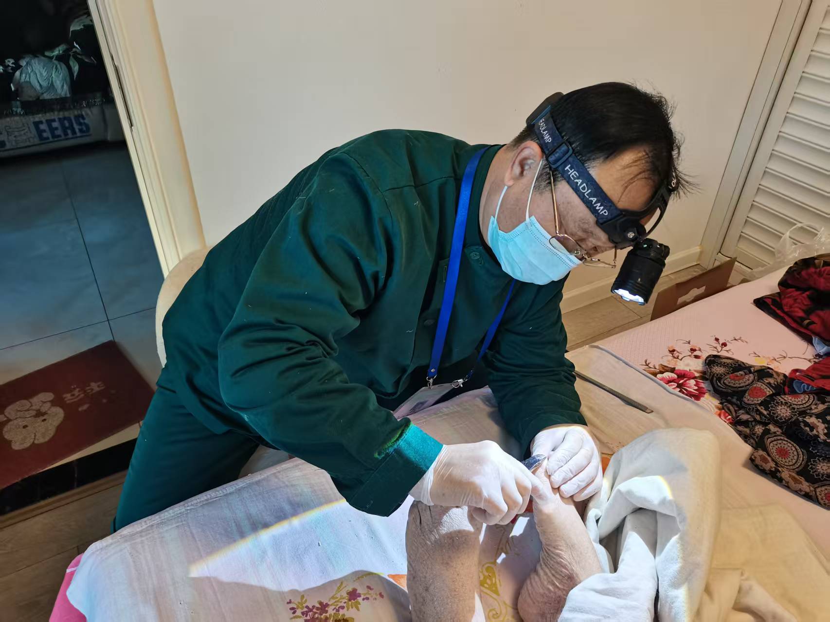 护理员王新中正在为侯阿姨的老伴提供修脚服务。受访者供图